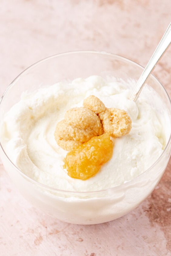Garlic and lemon paste being added to a bowl of greek yogurt.