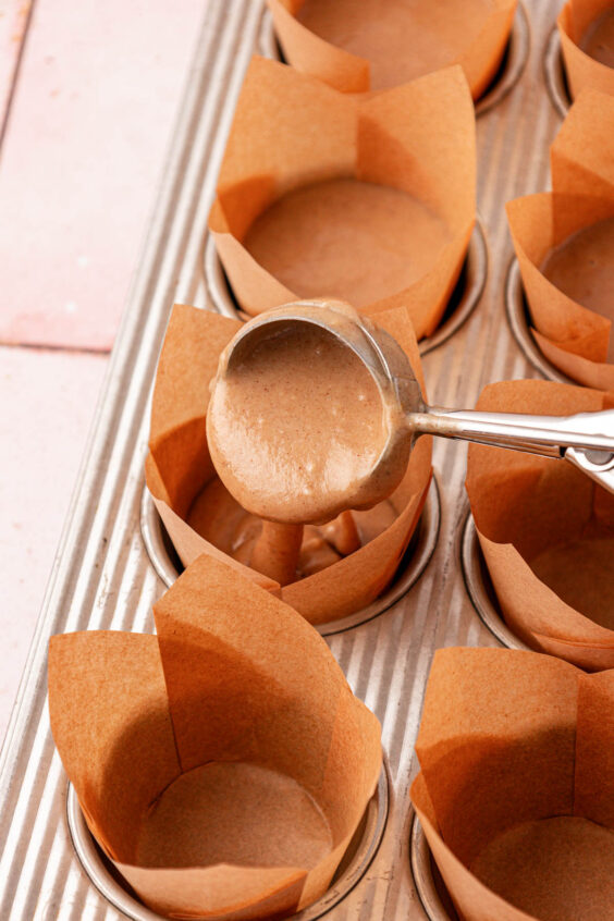 A cookie scoop portioning muffin batter out into liners.